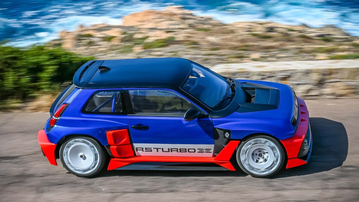 نمای جانبی Renault 5 Turbo 3E در کنار ساحل مدیترانه، با رنگ آبی و قرمز و بدنه عریض مخصوص رالی