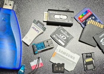 مجموعه‌ای از کارت‌های حافظه قدیمی با فرمت‌های مختلف (مانند SmartMedia، xD-Picture Card، Memory Stick Micro M2 و microSD) و یک رم ریدر (Card Reader) آبی رنگ.