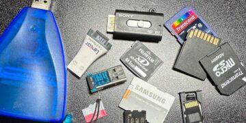 مجموعه‌ای از کارت‌های حافظه قدیمی با فرمت‌های مختلف (مانند SmartMedia، xD-Picture Card، Memory Stick Micro M2 و microSD) و یک رم ریدر (Card Reader) آبی رنگ.