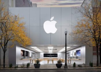 نمای بیرونی یک فروشگاه خرده‌فروشی اپل (Apple Store) با لوگوی بزرگ اپل روی نمای فلزی و درختان زرد پاییزی در جلوی آن.