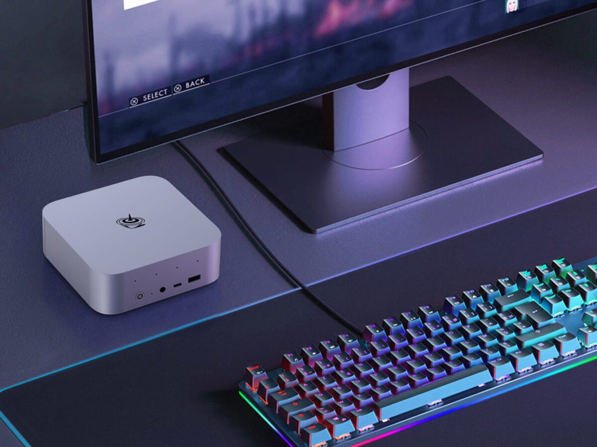 نمایی از مینی پی سی Beelink SER9 Max در رنگ سفید روی میز کامپیوتر کنار یک مانیتور و یک صفحه کلید