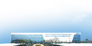 ساختمان یک کارخانه تولید تراشه CXMT در چین، یک سازه مدرن و وسیع با لوگوی CXMT در سمت راست، در فضای باز زیر آسمان روشن.