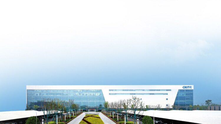 ساختمان یک کارخانه تولید تراشه CXMT در چین، یک سازه مدرن و وسیع با لوگوی CXMT در سمت راست، در فضای باز زیر آسمان روشن.