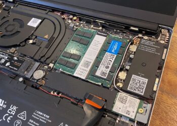 داخل لپتاپ Framework باز شده که ماژولهای رم Crucial و SSD را نشان میدهد، با یک باتری بزرگ و کانکتورهای داخلی.