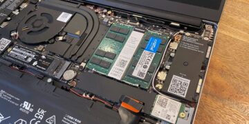 داخل لپ‌تاپ Framework باز شده که ماژول‌های رم Crucial و SSD را نشان می‌دهد، با یک باتری بزرگ و کانکتورهای داخلی.