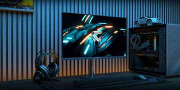 یک مانیتور گیمینگ Gigabyte GO27Q24 در یک محیط دسکتاپ گیمینگ، در کنار یک کیس کامپیوتر روشن، هدست و کیبورد مکانیکی.