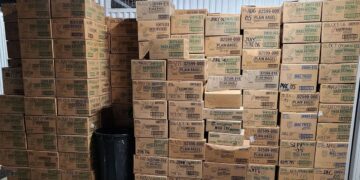 انباشته بزرگی از جعبههای مقوایی که عمدتاً با برچسبهایی مانند "HASH BROWNS" و "PLAIN BAGEL" و تاریخهای بین سالهای ۲۰۰۴ تا ۲۰۰۹ پوشانده شدهاند.