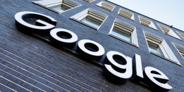 نمای بیرونی یک ساختمان آجری تیره با پنجرههای سفید، که لوگوی برجسته و سفید "Google" بر روی آن نصب شده است.