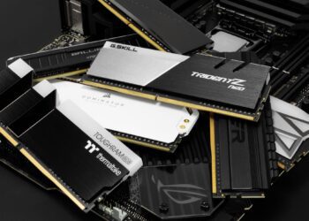 آرایشی از ماژولهای حافظه رم (RAM) با طرحهای مختلف هیتسینک (Heat Sink) در رنگهای سفید، سیاه و طلایی، که برندهایی مانند Corsair، G.Skill، Ballistix و Thermaltake روی آنها دیده میشود.