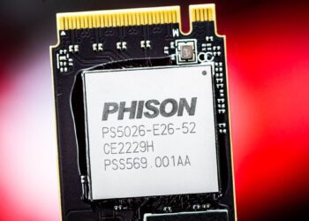 نمای نزدیک از یک تراشه کنترلر SSD با مارک "PHISON" و شماره مدل "PS5026-E26-52" بر روی یک برد مدار چاپی (PCB) با پسزمینه قرمز مات.