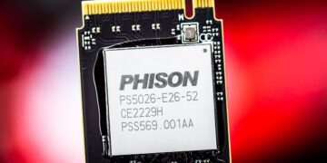 نمای نزدیک از یک تراشه کنترلر SSD با مارک "PHISON" و شماره مدل "PS5026-E26-52" بر روی یک برد مدار چاپی (PCB) با پس‌زمینه قرمز مات.