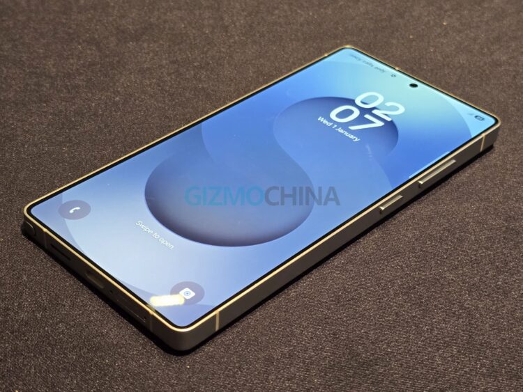 یک نمونه اولیه یا ماکت گوشی سامسونگ Galaxy S26 با لبه‌های تخت و براق و نمایشگر روشن که صفحه قفل آن ساعت و تاریخ را نشان می‌دهد.