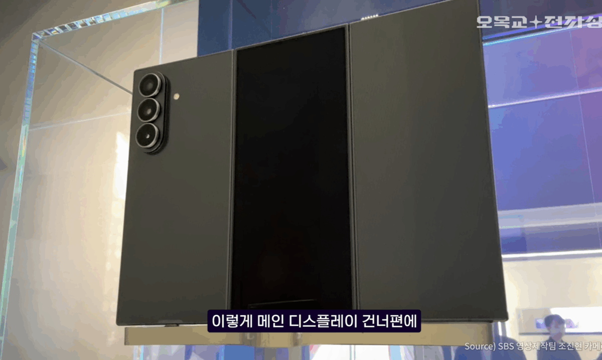 یک نمونه اولیه از گوشی تاشو سه‌لته‌ای (Tri-Fold) Samsung Galaxy Z با ماژول دوربین سه‌گانه، که در یک ویترین شیشه‌ای قرار گرفته و نمای پشتی آن دیده می‌شود.