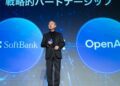 ماسایوشی سان، مدیرعامل سافت‌بانک، با کت و شلوار در حال سخنرانی روی صحنه، که در دو طرف او دایره‌های بزرگ آبی با لوگوی "SoftBank" و "OpenAI" نمایش داده شده است.