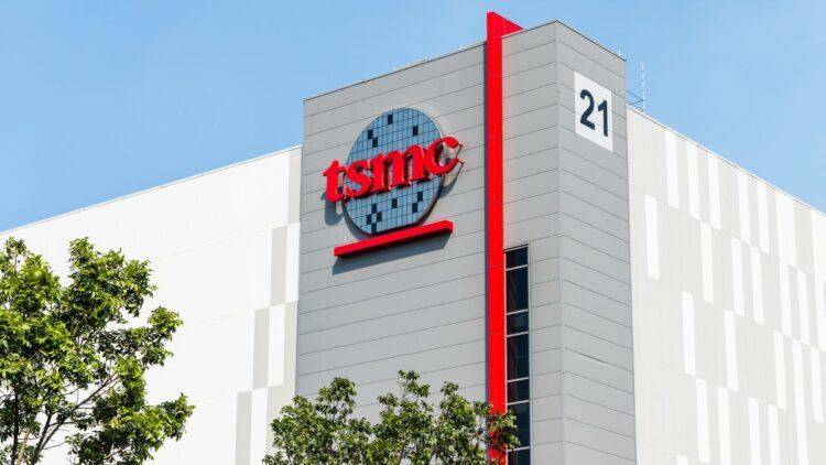 نمای بیرونی یک ساختمان TSMC با لوگوی قرمز رنگ شرکت، یک نوار عمودی قرمز و عدد "21" در گوشه ساختمان.