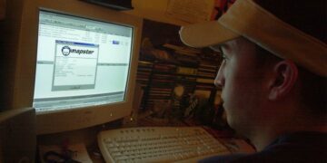 یک مرد در حال تماشای صفحه مانیتور CRT کامپیوتر در حال استفاده از برنامه اشتراک‌گذاری فایل Napster.