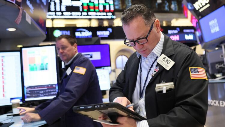یک کارگزار بورس (Stock Broker) در طبقه بورس نیویورک (NYSE) در حال بررسی داده‌ها روی یک تبلت.
