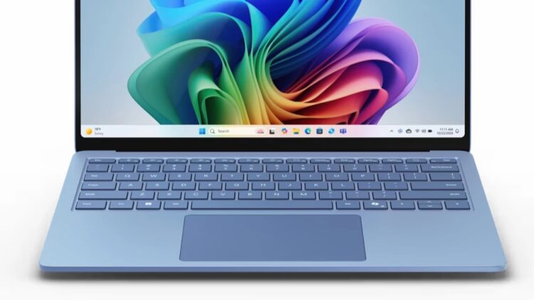نمای جلو لپ‌تاپ آبی رنگی که ویندوز ۱۱ را با پس‌زمینه رنگین‌کمانی روشن نمایش می‌دهد.