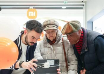 یک کارمند شیائومی در حال کمک به دو فرد مسن برای استفاده از یک تبلت با کیبورد در داخل فروشگاه شیائومی در پاریس.