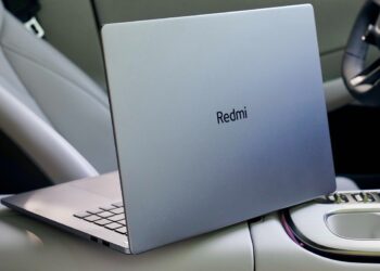 لپ‌تاپ Redmi با در باز در داخل یک ماشین، که لوگوی Redmi روی درب نقره‌ای آن دیده می‌شود.