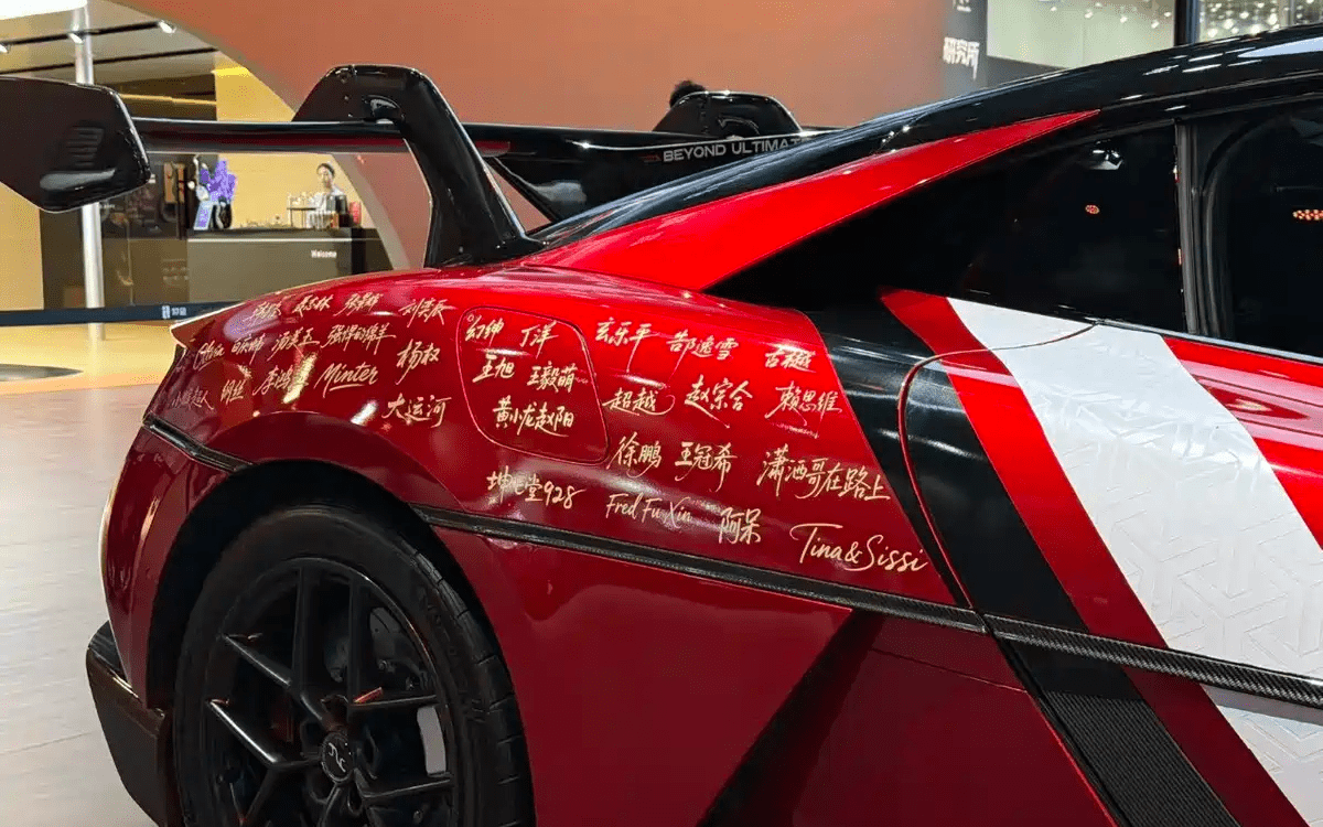 ابرخودرو Yangwang U9 Xtreme قرمز از نمای جلو در نمایشگاه، همراه با تخته اعلام رکورد Nürburgring کنار خودرو.