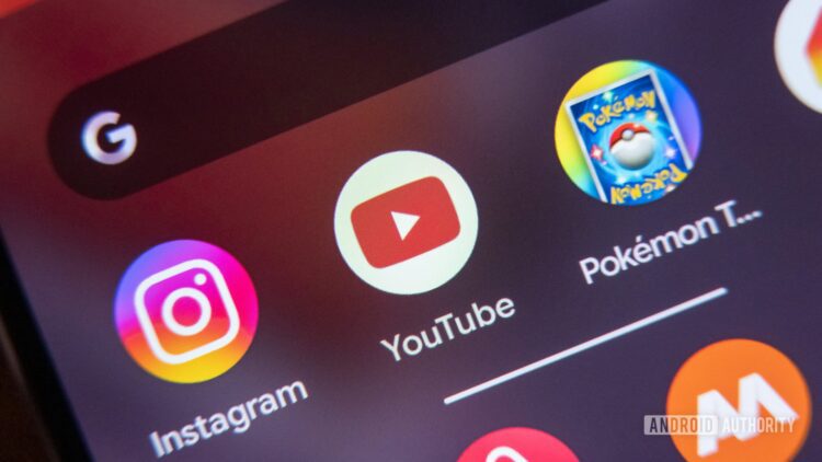 لوگوهای برنامه YouTube، Instagram و Pokemon TCG Live روی صفحه اصلی یک گوشی هوشمند.