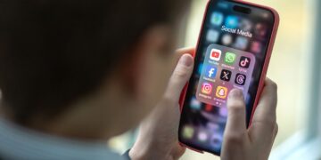 تصویری از آیکون برنامههای شبکههای اجتماعی روی یک گوشی در دستهای یک کودک