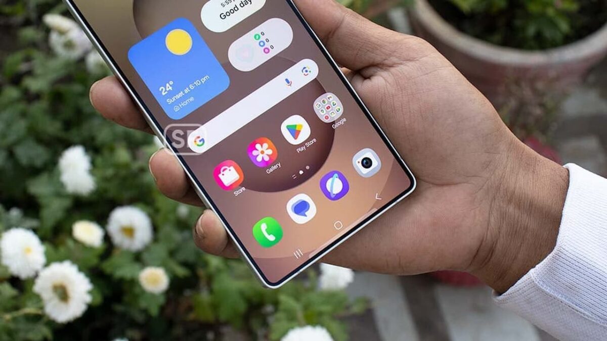 نمای نزدیک از یک گوشی هوشمند سامسونگ که در دست گرفته شده و صفحه اصلی آن ویجتهای آب و هوا و ساعت، به همراه آیکونهای گرد برنامه را در یک تم رنگی گرم نشان میدهد.