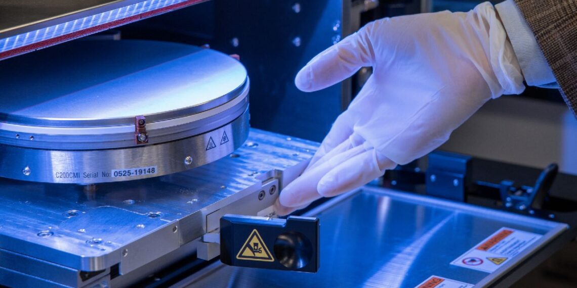 تراشهٔ سیلیکونی درون دستگاه ساخت نیمههادی، هنگام نصب و بررسی معماری سهبعدی با دستکش ایمنی در محیط آزمایشگاهی.