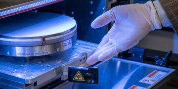 تراشهٔ سیلیکونی درون دستگاه ساخت نیمههادی، هنگام نصب و بررسی معماری سهبعدی با دستکش ایمنی در محیط آزمایشگاهی.