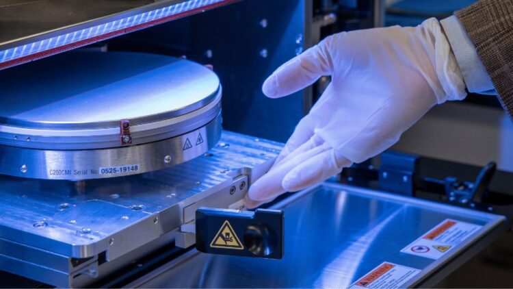 تراشهٔ سیلیکونی درون دستگاه ساخت نیمههادی، هنگام نصب و بررسی معماری سهبعدی با دستکش ایمنی در محیط آزمایشگاهی.