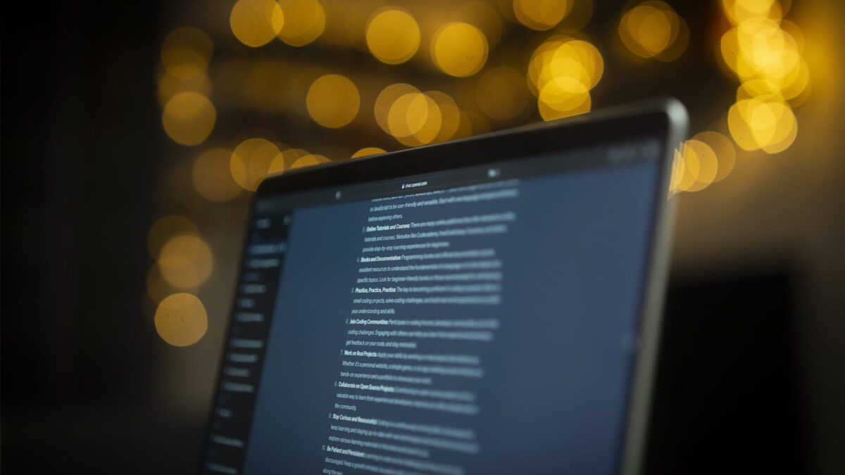 نمای لپ‌تاپی با صفحه‌نمایش حاوی نوشته‌های متنی، پس‌زمینه تاریک با افکت بوکه طلایی، تاکید بر محیط کاری دیجیتال