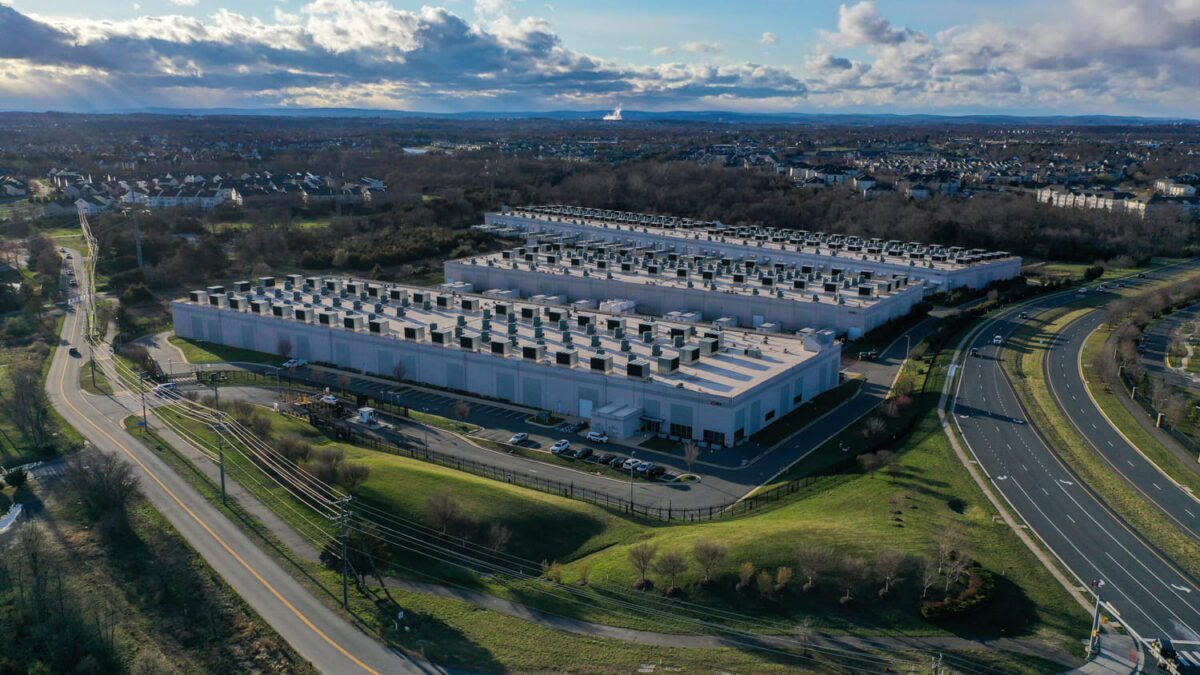 نمای هوایی از یک مجموعه بزرگ مرکز داده با ماژول‌ های خنک‌ سازی متعدد در حاشیه شهری، مرتبط با تحقیقات افزایش مصرف برق و فشار مراکز داده بر شبکه انرژی منطقه‌ای