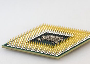 نمای نزدیک (ماکرو) از پین‌های طلایی اتصال در زیر یک پردازنده کامپیوتری (CPU).