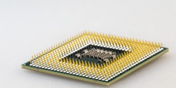 نمای نزدیک (ماکرو) از پین‌های طلایی اتصال در زیر یک پردازنده کامپیوتری (CPU).