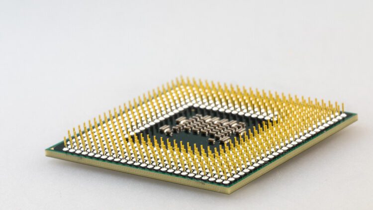 نمای نزدیک (ماکرو) از پین‌های طلایی اتصال در زیر یک پردازنده کامپیوتری (CPU).