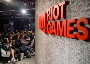نمای داخلی رویداد League of Legends با تمرکز بر لوگوی Riot Games روی دیوار و فضای سالن، مرتبط با برگزاری ایونت رسمی، مسابقات یا برنامه‌ های رقابتی Worlds