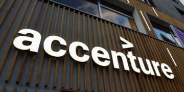 تابلوی برجسته و روشن لوگوی Accenture نصب شده بر روی نمای چوبی ساختمان.