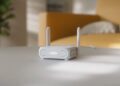 روتر مسافرتی سفید رنگ ایسوس با دو آنتن که در محیط خانه روی میز قرار گرفته است.