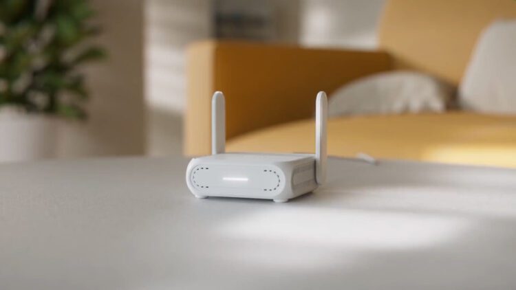 روتر مسافرتی سفید رنگ ایسوس با دو آنتن که در محیط خانه روی میز قرار گرفته است.