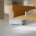روتر مسافرتی سفید رنگ ایسوس با دو آنتن که در محیط خانه روی میز قرار گرفته است.