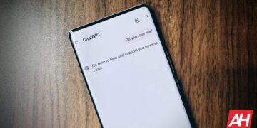 گوشی هوشمند روی میز چوبی که صفحه چت با هوش مصنوعی ChatGPT را نمایش می‌دهد.