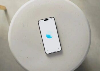 نمای بالاسری از یک گوشی هوشمند قرارگرفته روی میز گرد روشن با رابط کاربری ChatGPT Voice، نمایش انیمیشن صوتی آبی‌رنگ و اشاره به قابلیت مکالمه صوتی پیشرفته هوش مصنوعی