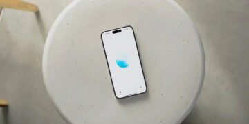 نمای بالاسری از یک گوشی هوشمند قرارگرفته روی میز گرد روشن با رابط کاربری ChatGPT Voice، نمایش انیمیشن صوتی آبی‌رنگ و اشاره به قابلیت مکالمه صوتی پیشرفته هوش مصنوعی