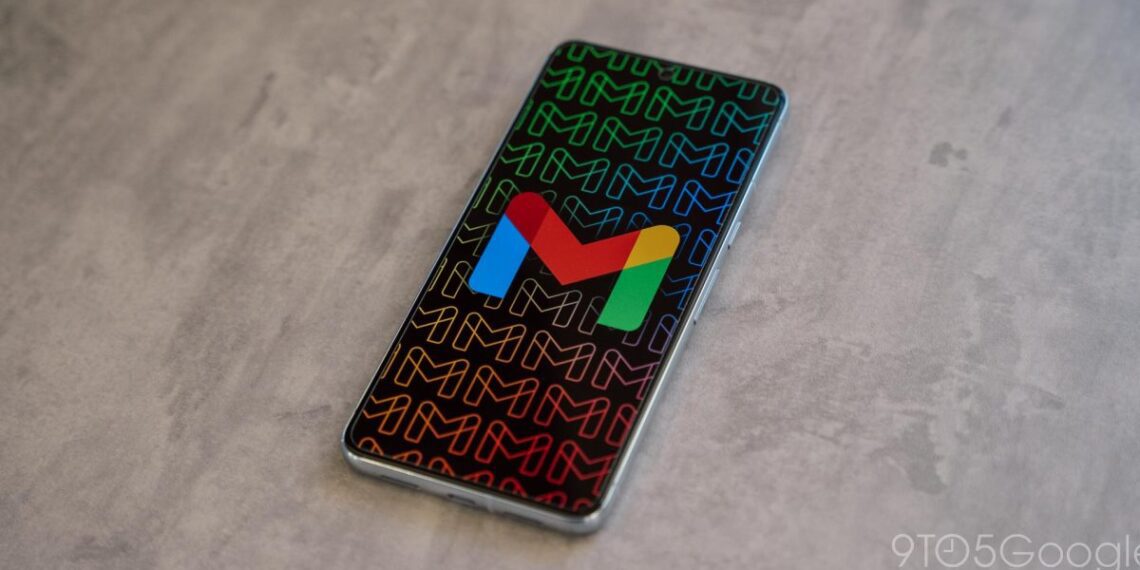 گوشی هوشمندی که آیکون رنگی جیمیل را روی پس‌زمینه‌ای با الگوی تکرار شونده حرف M نشان می‌دهد.