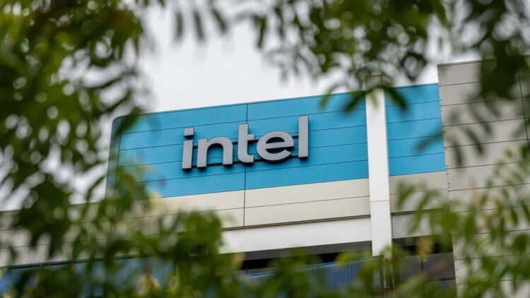 تابلوی لوگوی "intel" روی نمای ساختمان، که از میان شاخ و برگ درختان دیده میشود.