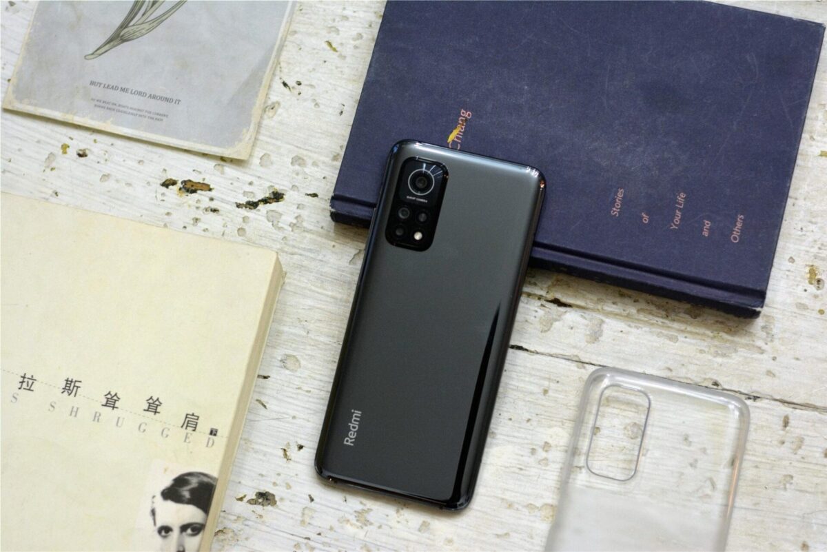 نمای پشت یک گوشی هوشمند ردمی مشکی براق روی میز چوبی سفید.