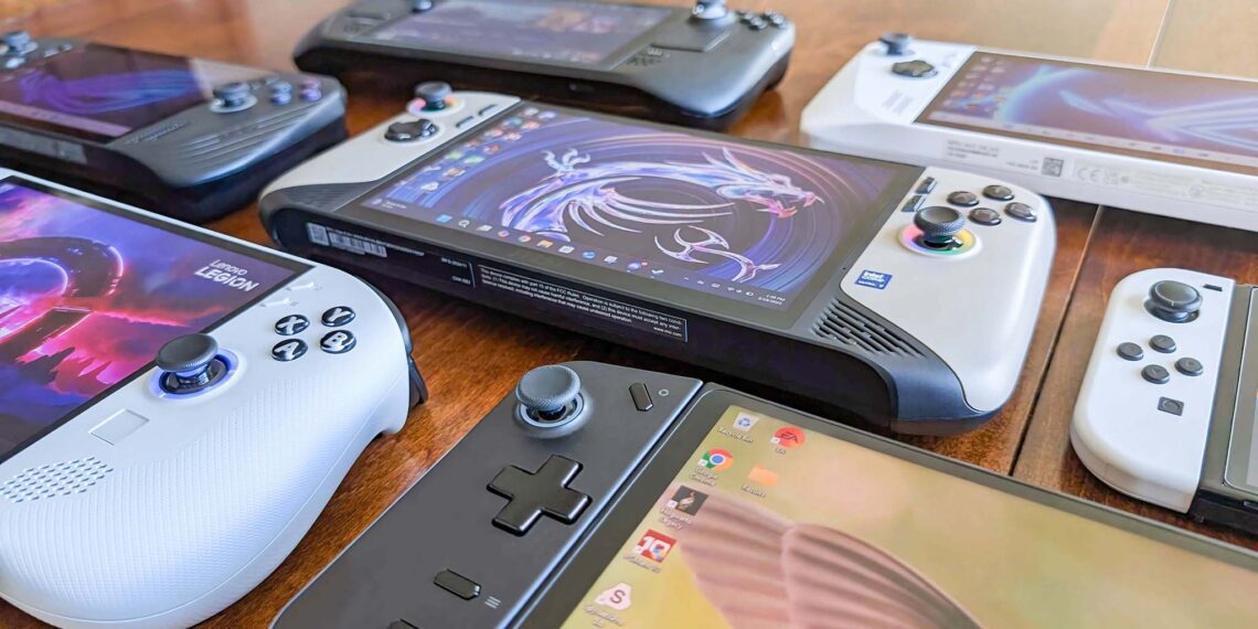 مجموعه‌ای از کنسول‌های بازی دستی مختلف (مانند استیم دک و لنوو لیژن) که روی یک میز چوبی چیده شده‌اند.