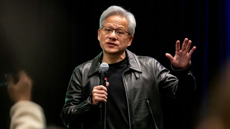 جنسن هوانگ با کاپشن چرمی مشکی معروف خود در حال صحبت کردن در یک رویداد عمومی.