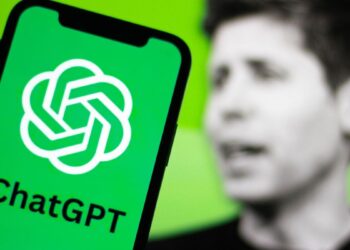 لوگوی چتجیپیتی روی صفحه گوشی در مقابل تصویر محو سام آلتمن.